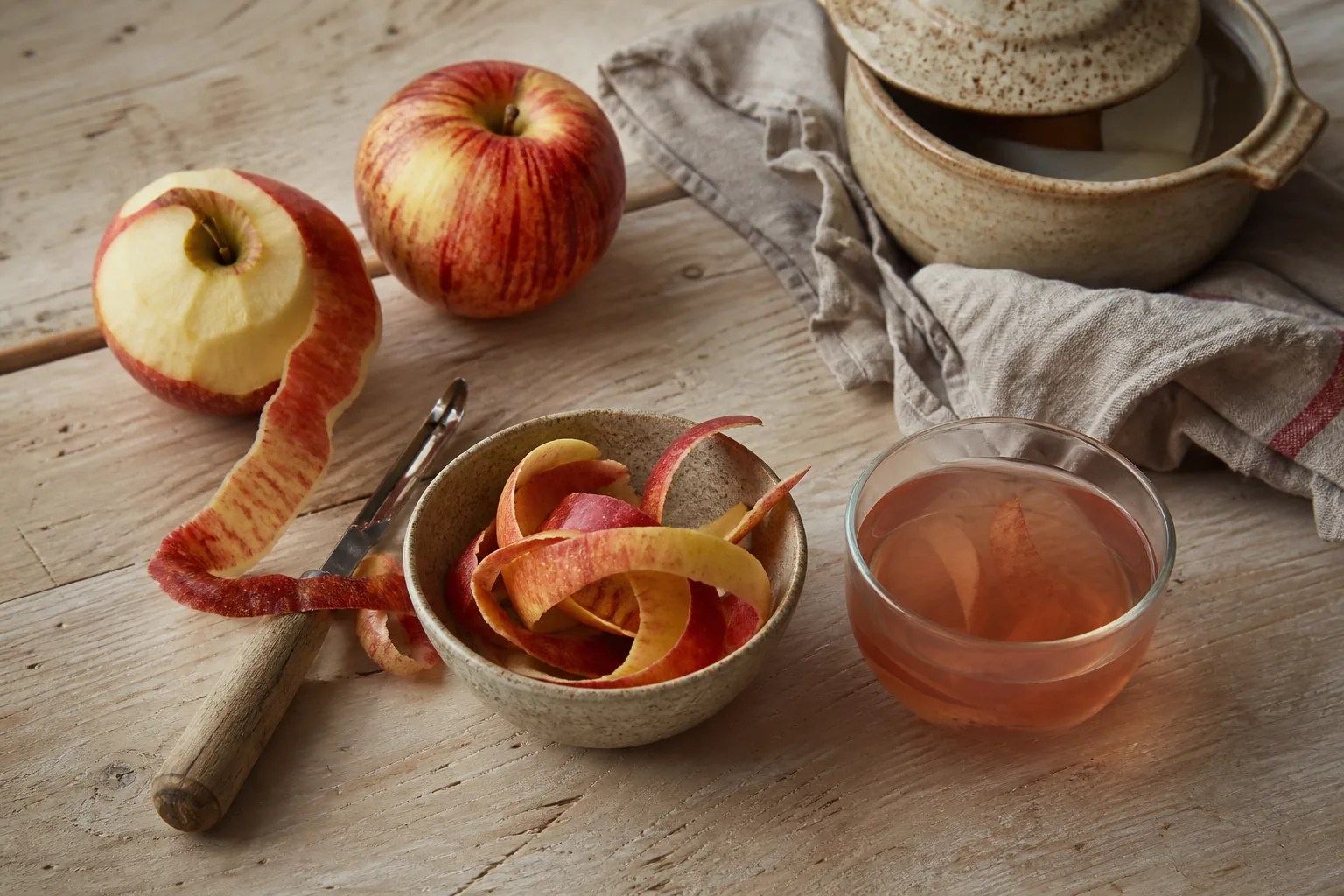 Freshly washed apple peel, whole apple, cinnamon-free simple infusion, and compost bowl.